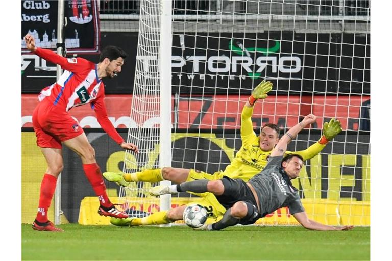 Tim Kleindienst (l.) macht das Tor zum 1:1 gegen Torhüter Christian Mathenia (M.) und Oliver Sorg. Foto: Tom Weller/dpa