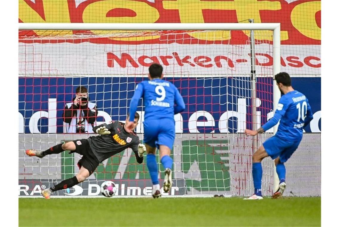 Tim Kleindienst von Heidenheim (r) trifft zum 0:3 gegen den Regensburger Torwart Alexander Meyer (2.v.l.). Foto: Armin Weigel/dpa