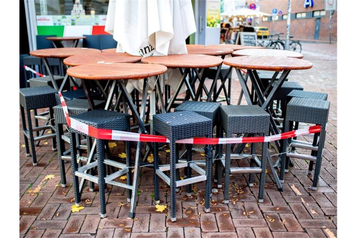 Tische und Stühle stehen vor einer Pizzeria in Hannover. Der Teil-Lockdown könnte angesichts weiter hoher Infektionszahlen noch länger andauern. Foto: Hauke-Christian Dittrich/dpa