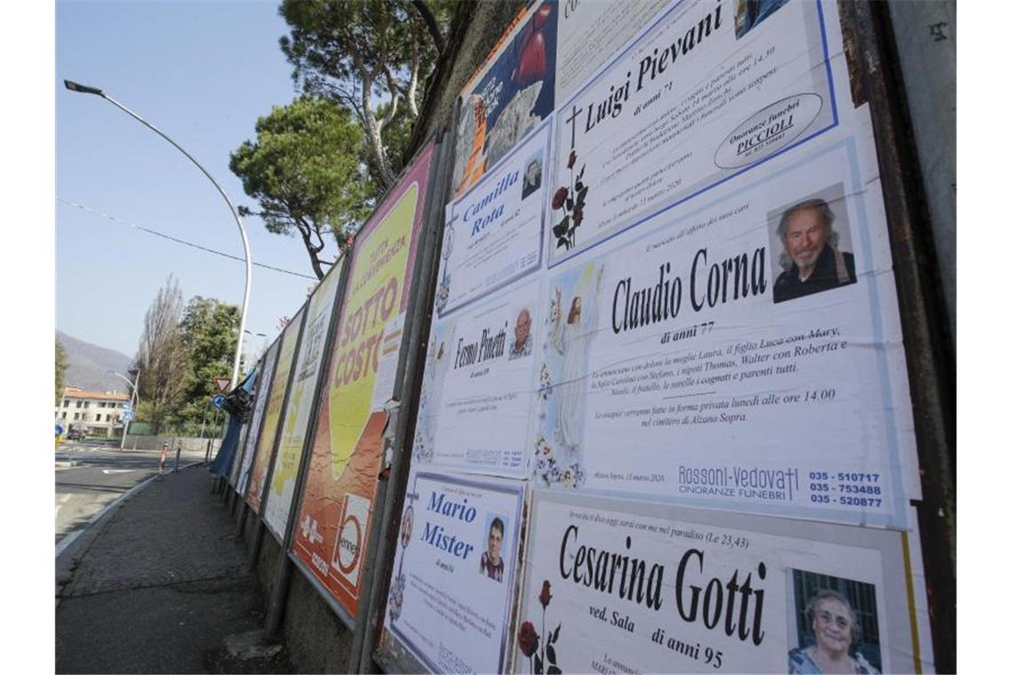 Todesanzeigen auf einer Tafel am Rand einer leeren Straße in Alzano Lombardo unweit von Bergamo. Foto: Luca Bruno/AP/dpa