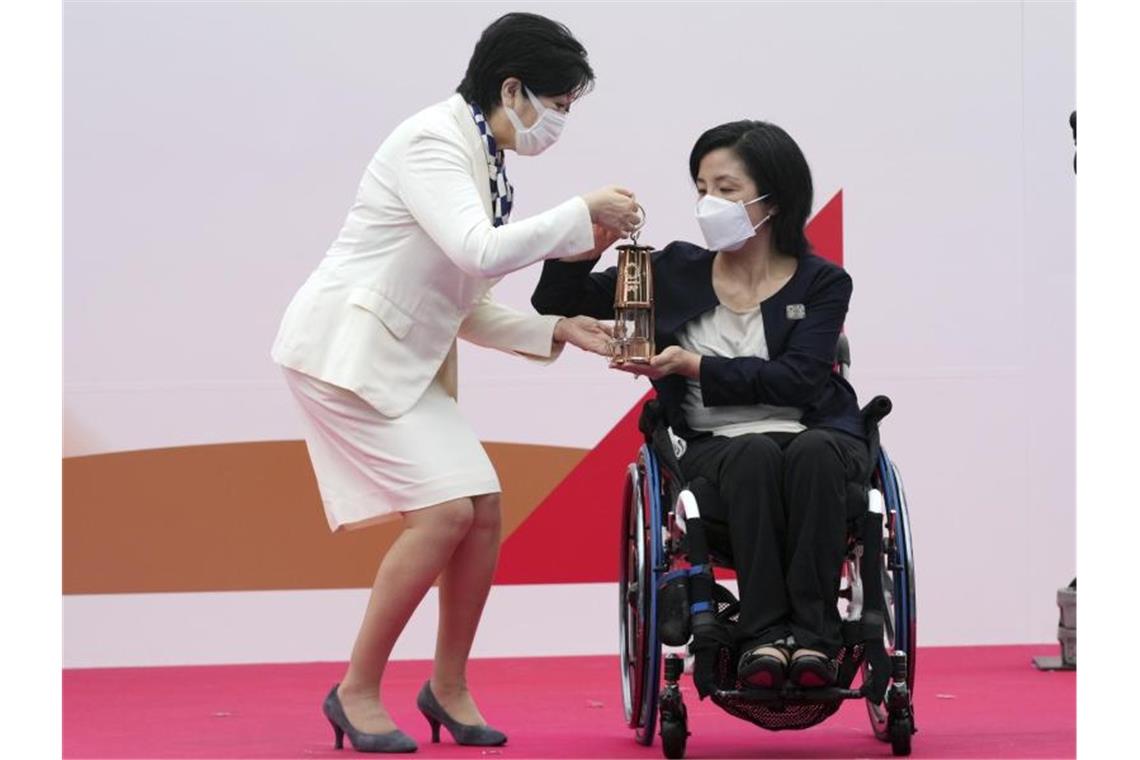 Tokios Gouverneurin Yuriko Koike (l) erhält eine Laterne mit der olympischen Flamme von Aki Taguchi, offizielle Botschafterin des Tokio 2020 Fackellaufs. Foto: Eugene Hoshiko/AP/dpa