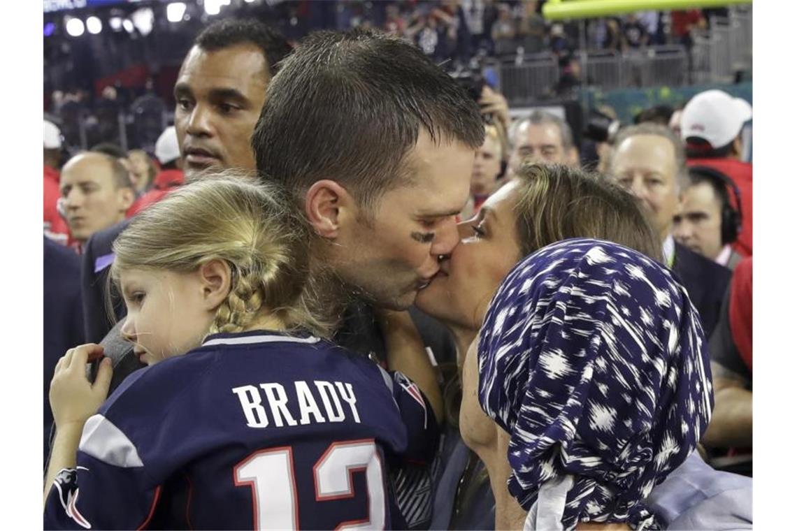 Der Kosmos der Quarterback-Stars Mahomes und Brady Tom Brady von den New England Patriots hält Tocher Vivian auf dem Arm und küsst seine Frau Gisele Bündchen, die Bradys Mutter Galynn (vorn) den Arm über die Schulter gelegt hat. Foto: Patrick Semansky/AP/dpa