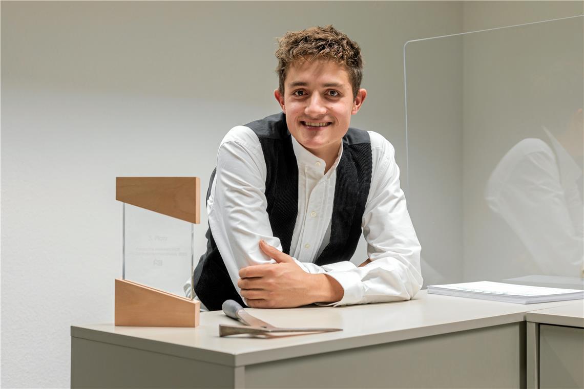 Tom Seel aus Murrhardt ist einer der besten Dachdecker Tom Seel mit der Auszeichnungsstele, auf der in zarter Schrift „Dritter Platz Deutsche Meisterschaft im Dachdeckerhandwerk 2023“ steht, und seinem Schieferhammer, der beim Herstellen der Dach- und Fassadensteine verwendet wird. Foto: Stefan Bossow