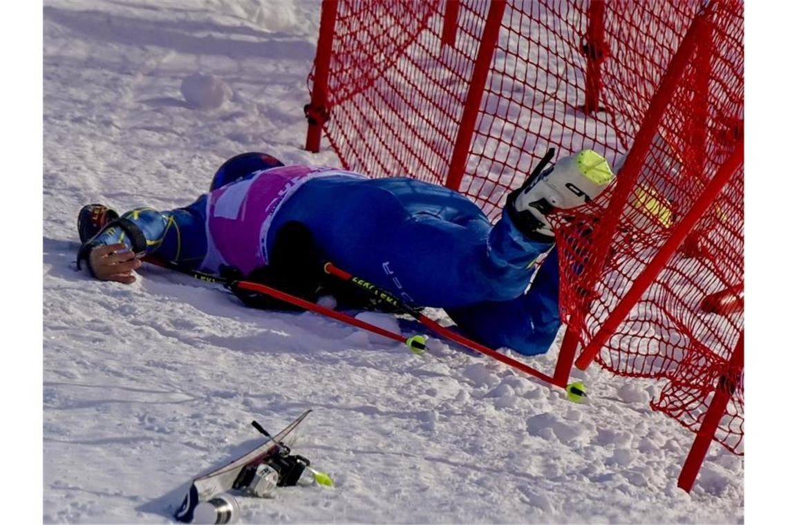 Tommy Ford aus den USA liegt nach einem Sturz verletzt am Fangnetz auf dem Boden. Foto: Jean-Christophe Bott/KEYSTONE/dpa