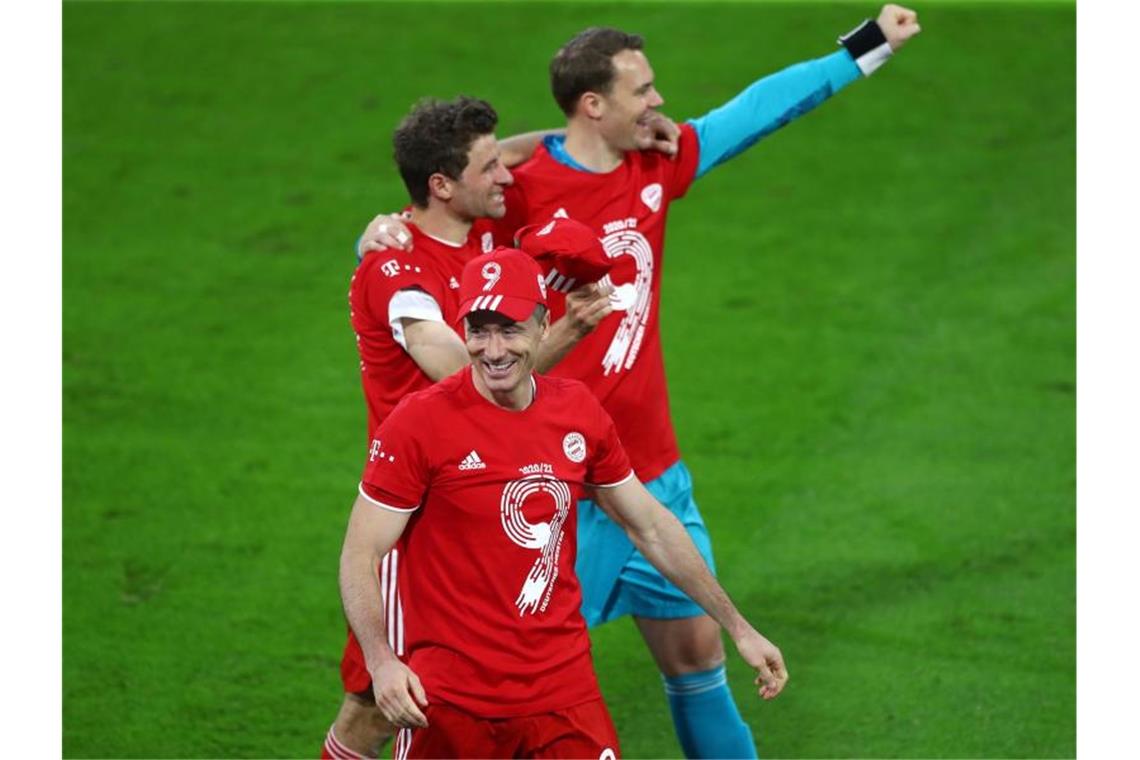 Torjäger Robert Lewandowski (v.), Thomas Müller und Torwart Manuel Neuer (r) jubeln nach dem Titelgewinn. Foto: Peter Kneffel/dpa-Pool/dpa