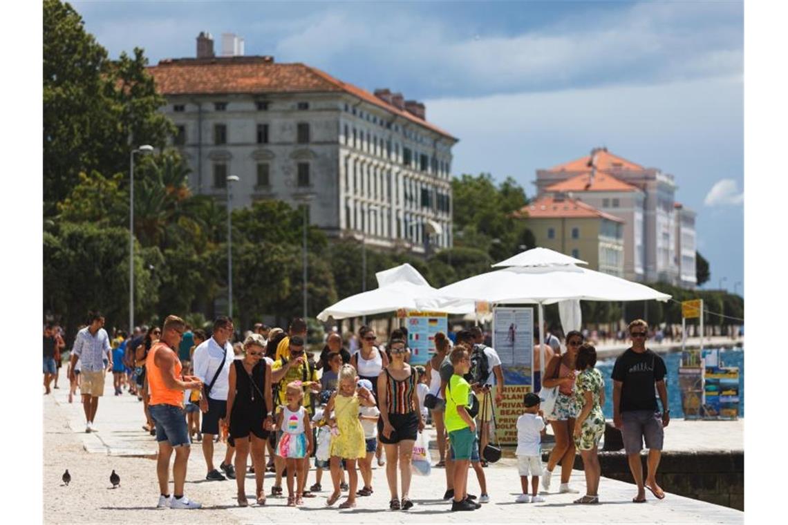 Touristen an der Uferpromenade von Zadar. Nach Angaben der kroatischen Tourismusindustrie halten sich derzeit etwa 30.000 Urlauber aus Deutschland in den von der Reisewarnung betroffenen Gebieten auf. Foto: Marko Dimic/Pixsell/Xinhua/dpa