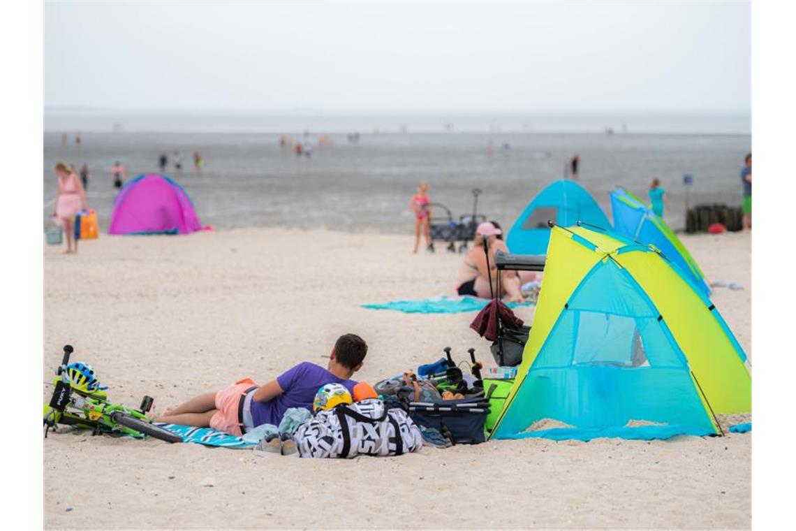 „Kein super Strandwetter“: Entspannte Lage zum Ferienbeginn Touristen entspannen am Badestrand von Schillig in Niedersachsen. Foto: Mohssen Assanimoghaddam/dpa