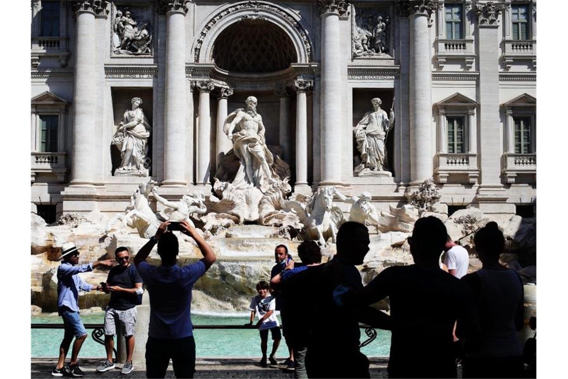 Touristen fotografieren den Trevi-Brunnen in Rom. Angesichts steigender Infektionszahlen wappnen sich manche Länder mit neuen Regeln. Foto: Evandro Inetti/ZUMA Wire/dpa