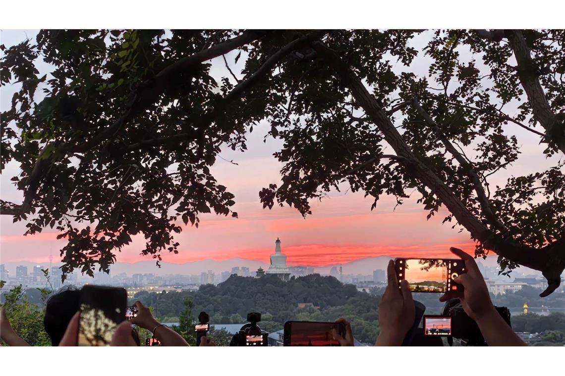 Bilder des Tages Touristen fotografieren mit ihren Handys den farbenfrohen Sonnenuntergang über der chinesischen Hauptstadt.