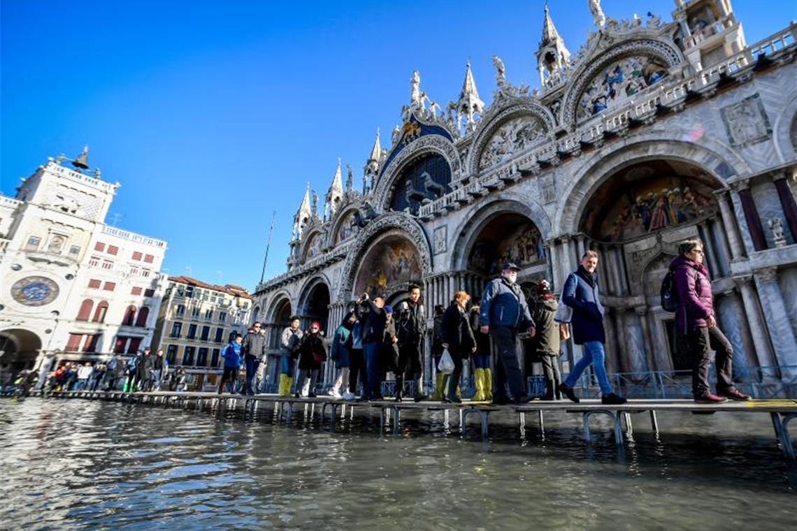 Touristen gehen über Stege vor dem Markusdom. Wegen des verheerenden Hochwassers haben viele Touristen ihre Reisen in die Lagunenstadt storniert. Foto: Claudio Furlan/LaPresse via ZUMA Press/dpa