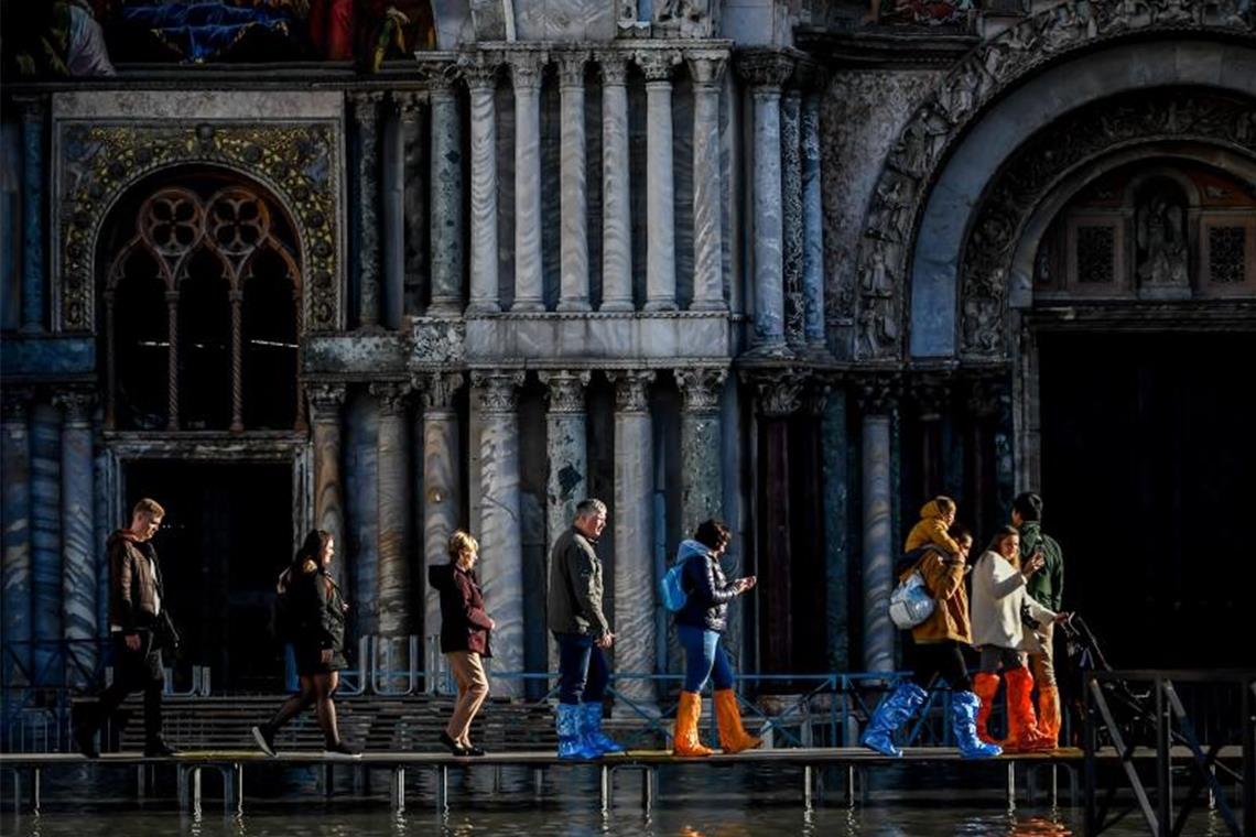 Venedig kämpft gegen neue Fluten - Schäden am Markusdom Touristen gehen vor dem Markusdom über Stege, die über das Hochwasser führen. Foto: Claudio Furlan/LaPresse via ZUMA Press/dpa