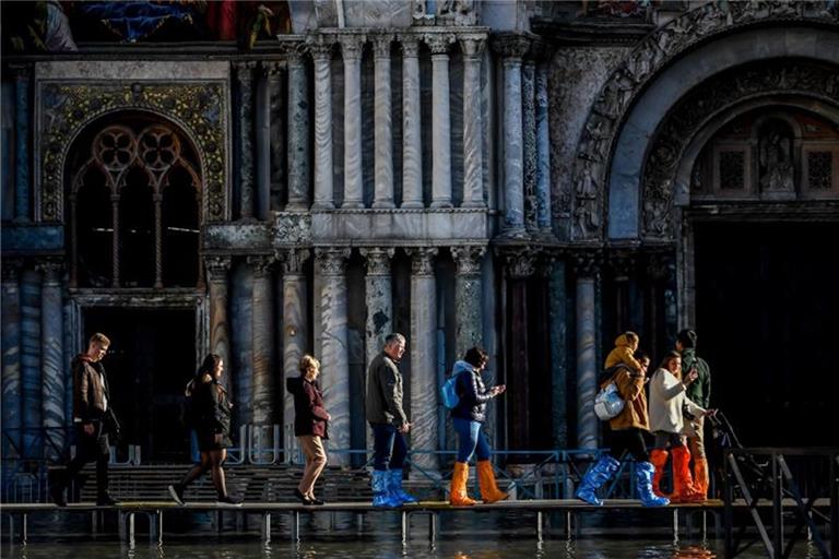 Touristen gehen vor dem Markusdom über Stege, die über das Hochwasser führen. Foto: Claudio Furlan/LaPresse via ZUMA Press/dpa