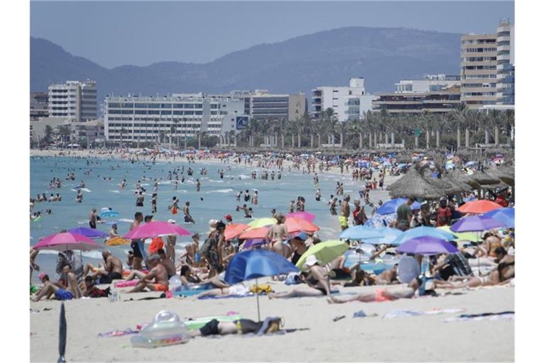 Touristen genießen die Sonne am Strand von Arenal. Foto: Clara Margais/dpa