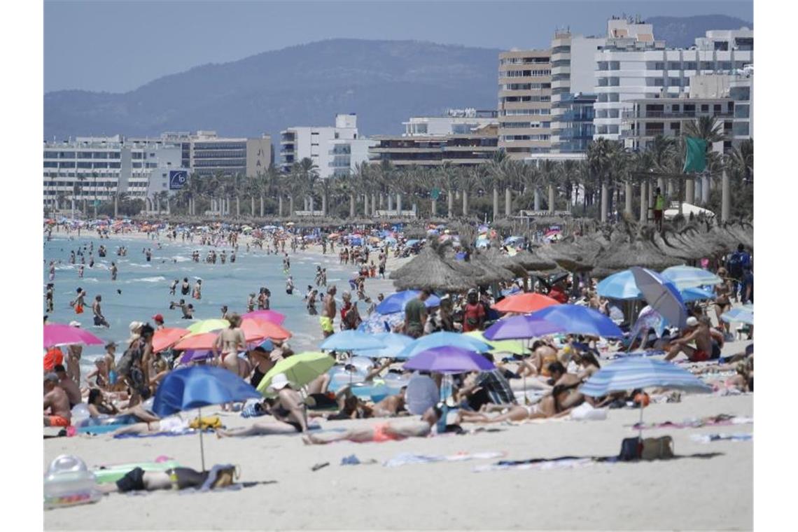 Touristen genießen die Sonne am Strand von Arenal. Wegen stark steigender Corona-Infektionszahlen stuft die Bundesregierung am Sonntag ganz Spanien und damit auch Mallorca und die Kanaren als Risikogebiet ein. Foto: Clara Margais/dpa