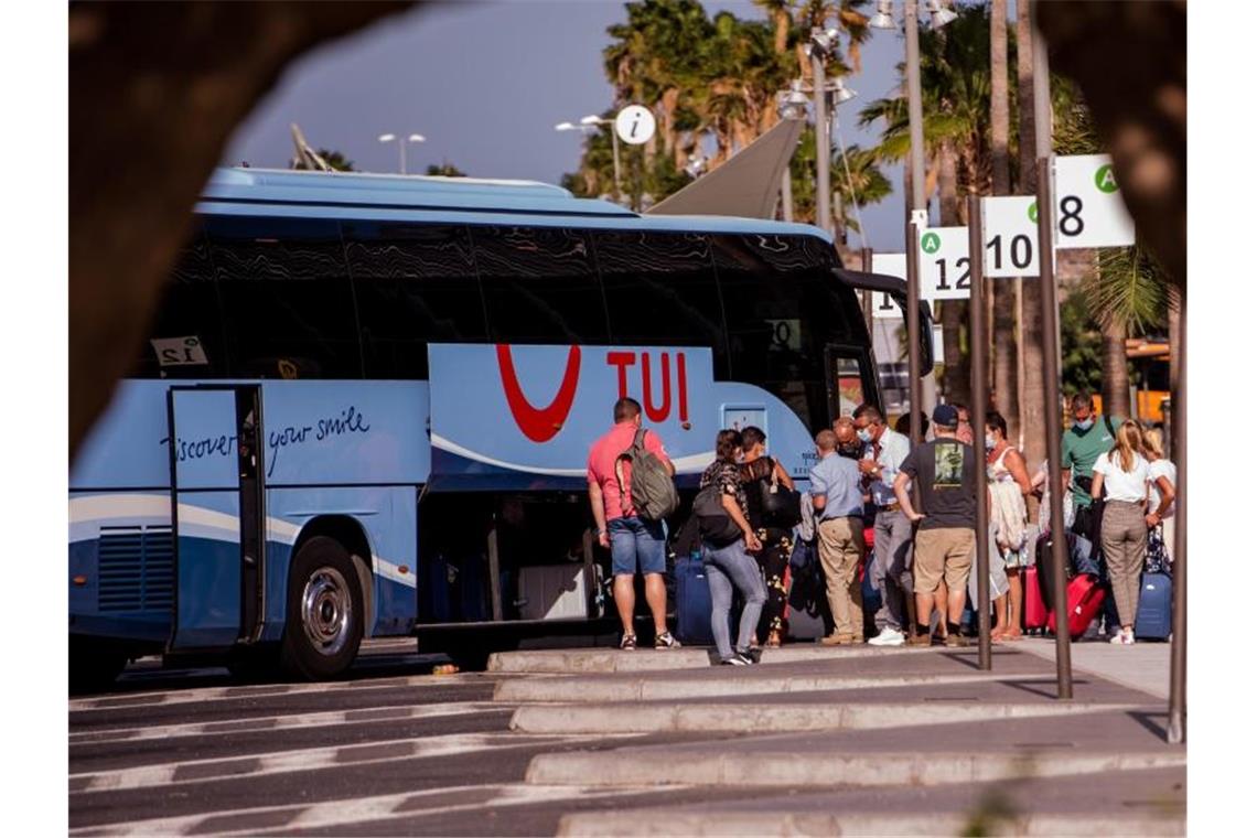 Touristen mit Mundschutz holen ihr Gepäck aus einem Bus des Tourismuskonzerns Tui nahe des Flughafens auf Tenerife. Foto: ARTuro Jimenez/dpa