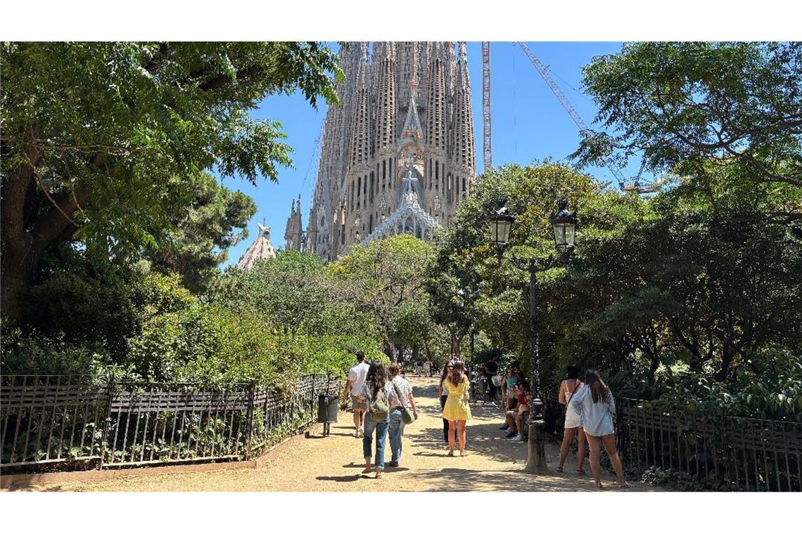 Touristen suchen bei großer Hitze den Schatten auf der Placa de la Sagrada Familia vor der gleichnamigen Basilika in Barcelona. (Archivbild)