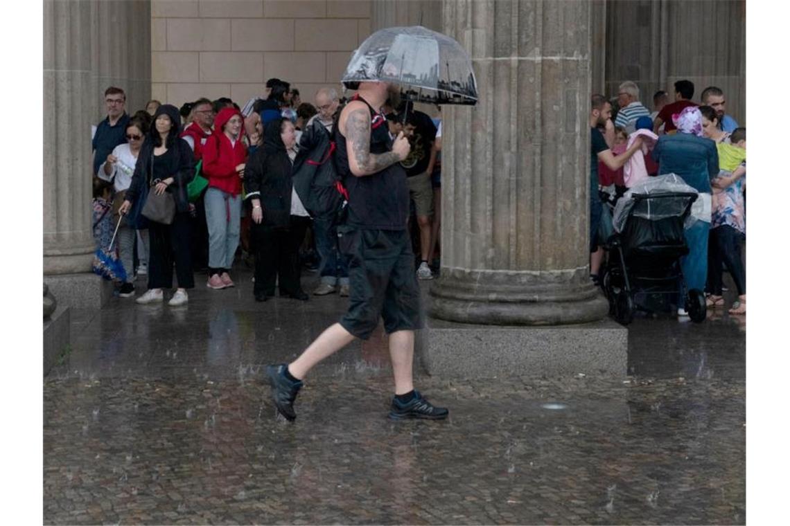 Gewitter ziehen nach Osten - Waldbrand breitet sich aus Touristen suchten am Pariser Platz in Berlin vor dem Regen Schutz. Foto: Paul Zinken