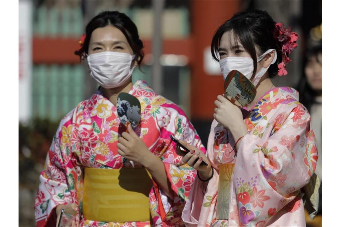 Touristinnen in Tokio tragen bei einem Tempelbesuch Mundschutz. Foto: Jae C. Hong/AP/dpa
