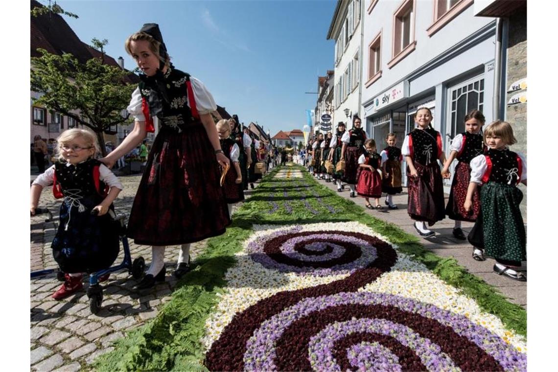 Trachtenträgerinnen in Hüfingen neben einem traditionellen Blumenteppich. Foto: Patrick Seeger/Archivbild