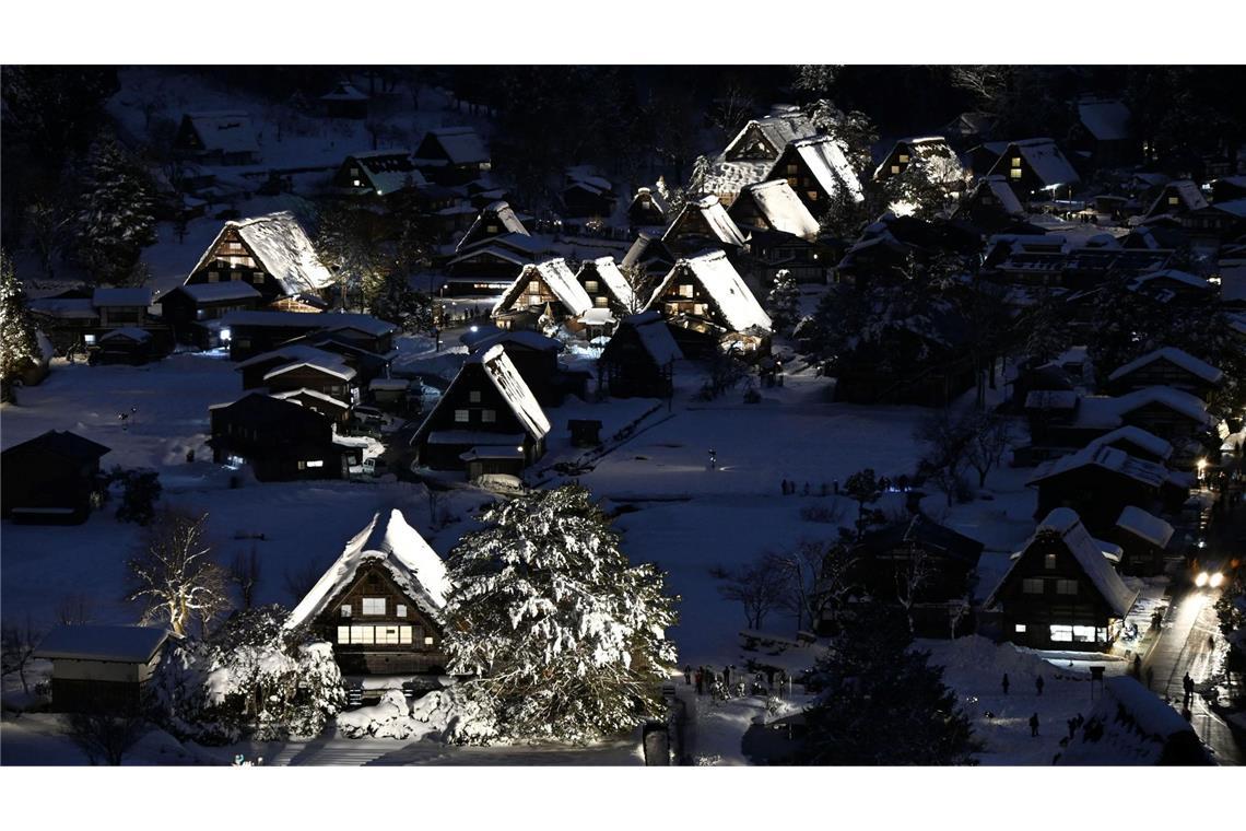 Traditionelle Strohdachhäuser sind mit Schnee bedeckt und werden im zum Weltkulturerbe gehörenden Dorf Shirakawa-go in der Präfektur Gifu in Zentraljapan beleuchtet.