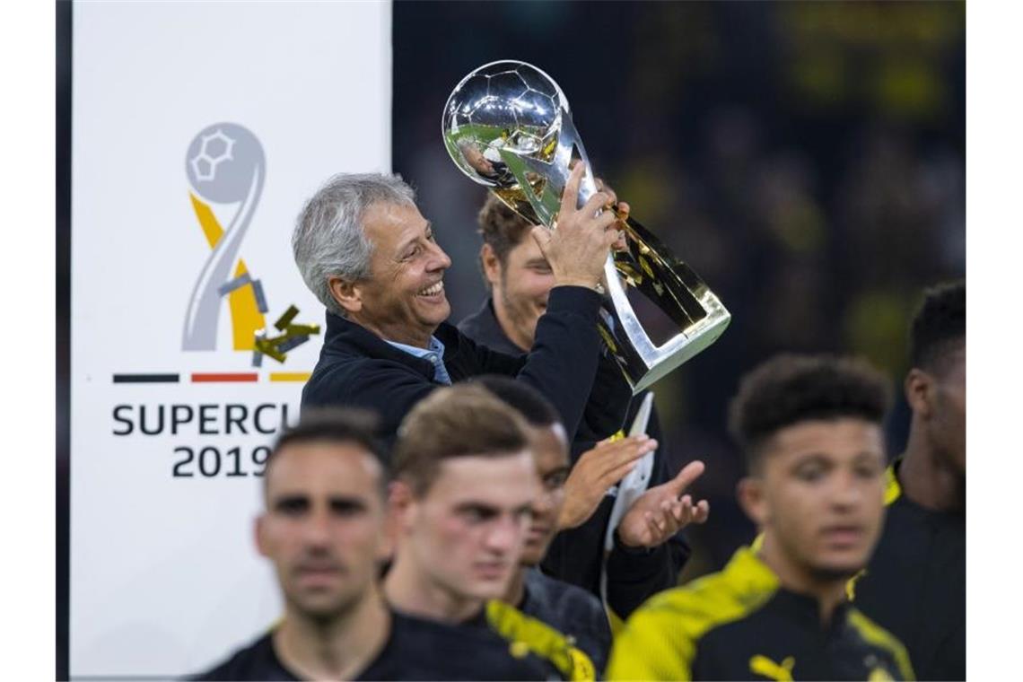 Trägt nach der Siegerehrung den Pokal eigenhändig vom Podest: Dortmunds Trainer Lucien Favre mit Supercup. Foto: Guido Kirchner