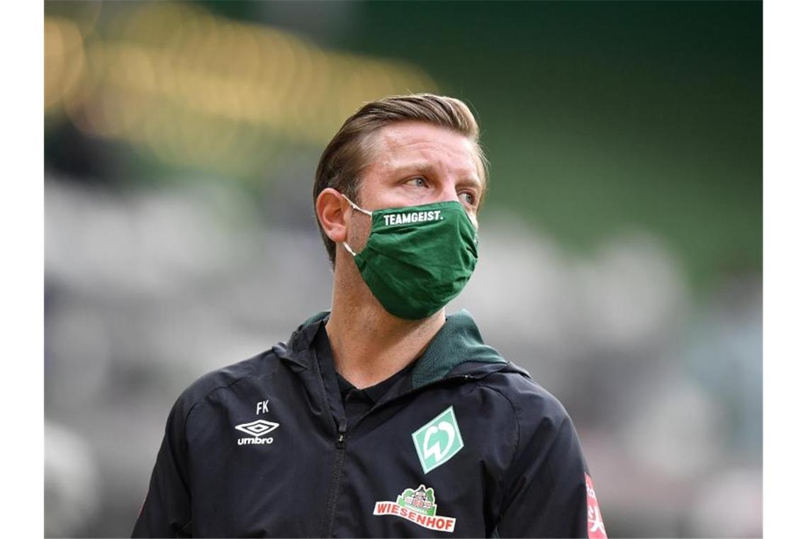 Trainer Florian Kohfeldt trägt eine Maske mit dem Schriftzug "Teamgeist". Foto: Martin Meissner/AP-Pool/dpa/Archivbild