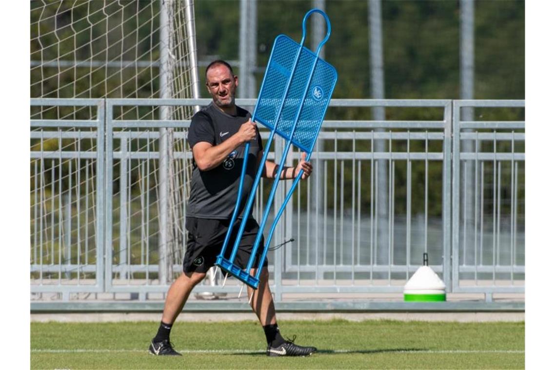 Trainer Frank Schmidt trägt beim Trainingsauftakt des FC Heidenheim einen Spieler-Dummy. Foto: Stefan Puchner/dpa