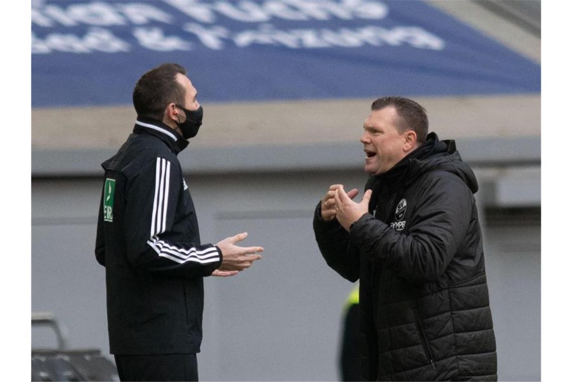 Trainer Uwe Koschinat (r) von Sandhausen diskutiert. Foto: Bernd Thissen/dpa