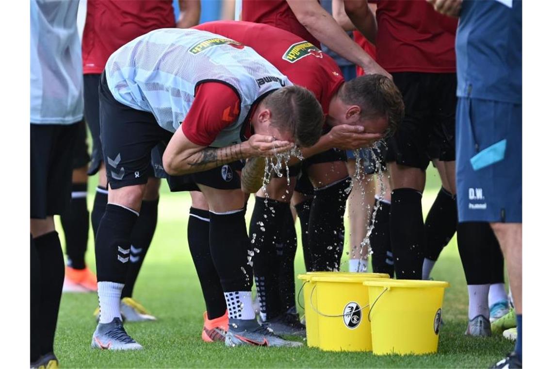 Zwei Spiele an einem Tag des SC Freiburg Trainingsauftakt SC Freiburg, Mike Frantz (l) und Lukas Kübler (r) werfen sich Wasser ins Gesicht. Foto: Patrick Seeger