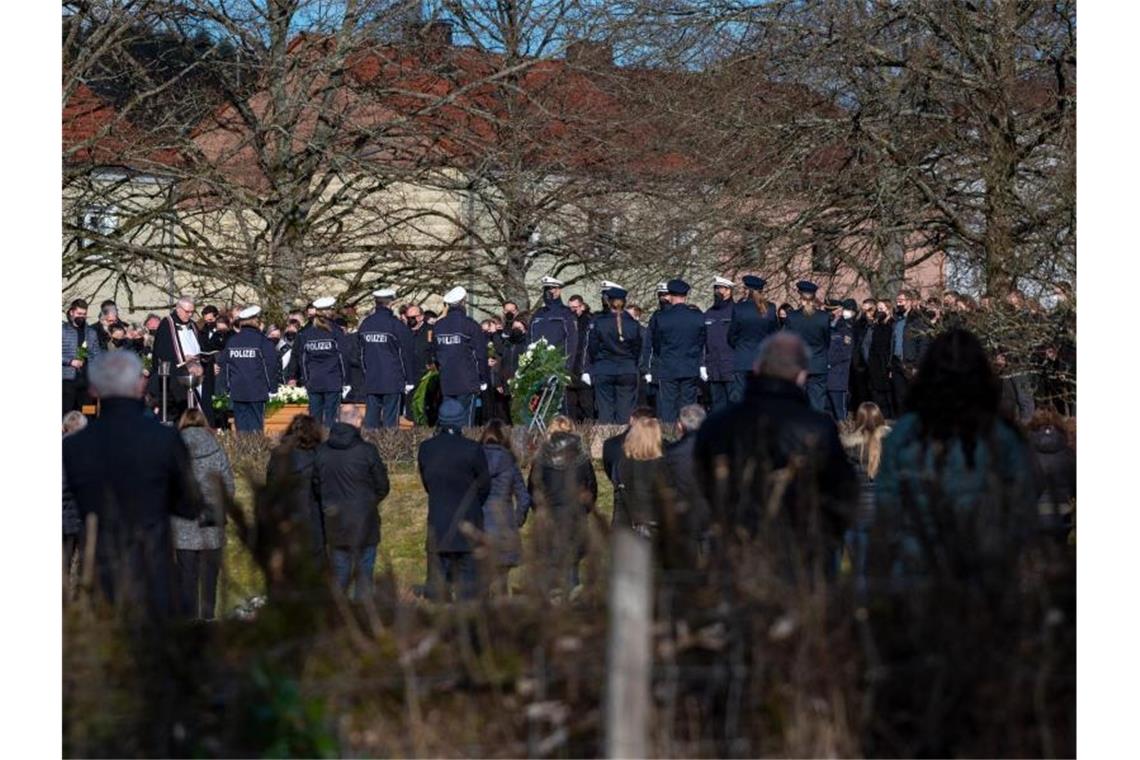 Trauergäste, darunter viele Polizisten, stehen am Grab bei der Beisetzung des Polizisten in Freisen. Foto: Harald Tittel/dpa