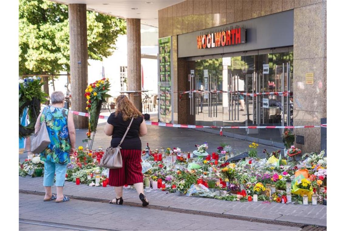 Trauerkerzen und Blumen liegen vor dem Kaufhaus, in dem der Täter Menschen mit einem Messer attackiert hatte. Foto: Nicolas Armer/dpa
