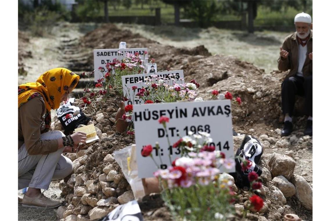 Trauernde beten an den Gräbern der bei einer Explosion in der Kohlegrube im türkischen Soma getöteten Bergleute. Foto: Tolga Bozoglu/EPA/dpa