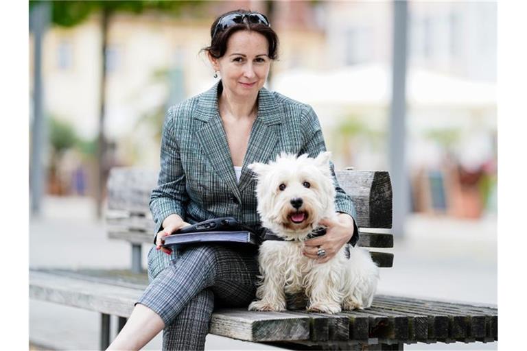 Trauerrednerin Jasmin Wagenblaß sitzt mit ihrem Hund „Nino“, einem Westhighland White Terrier, auf einer Bank. Foto: Uwe Anspach/Archivbild