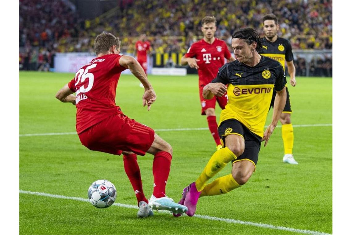 Treffen im Bundesliga-Topspiel aufeinander: Dortmunds Nico Schulz (r) und Bayerns Thomas Müller. Foto: Guido Kirchner/dpa