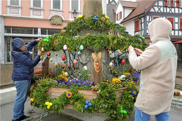 Trotz des regnerischen Wetters dekorieren die Landfrauen die Girlanden des Murrhardter Osterbrunnens. Foto: Stefan Bossow