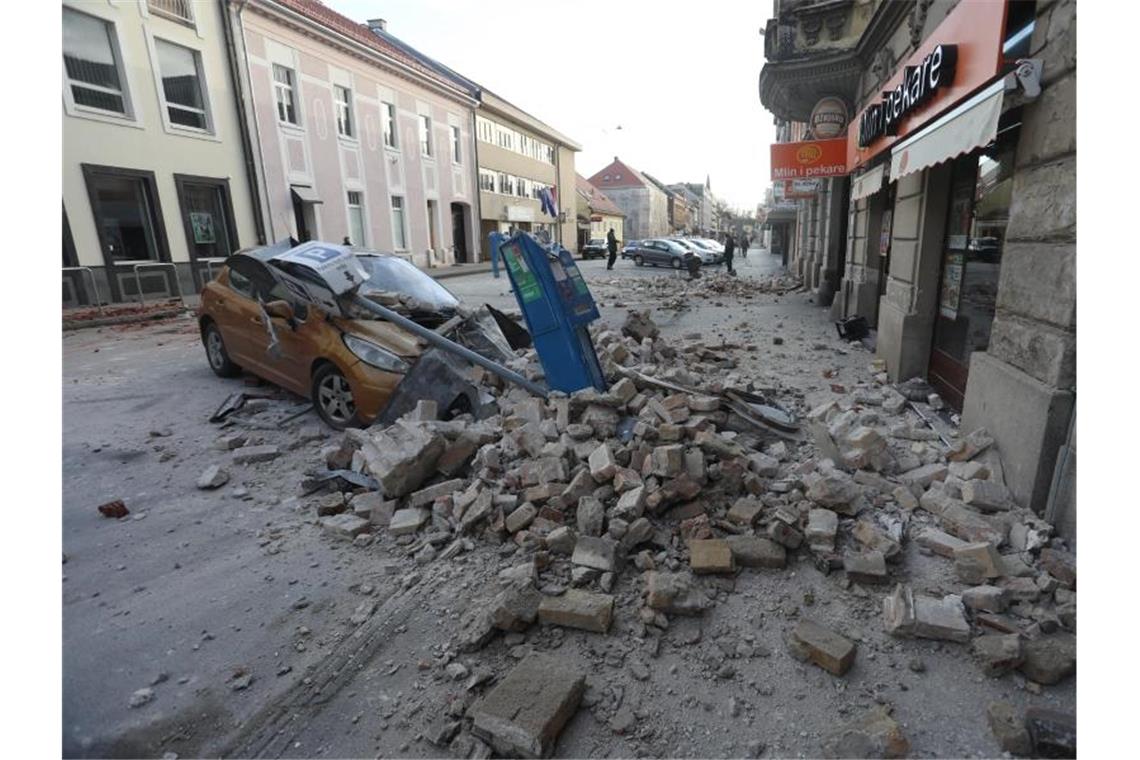 Trümmer eines durch ein Erdbeben eingestürzten Hauses bedecken ein Fahrzeug, das an einer Straße in Sisak steht. Foto: Marin Tironi/Pixsell/Xinhua/dpa