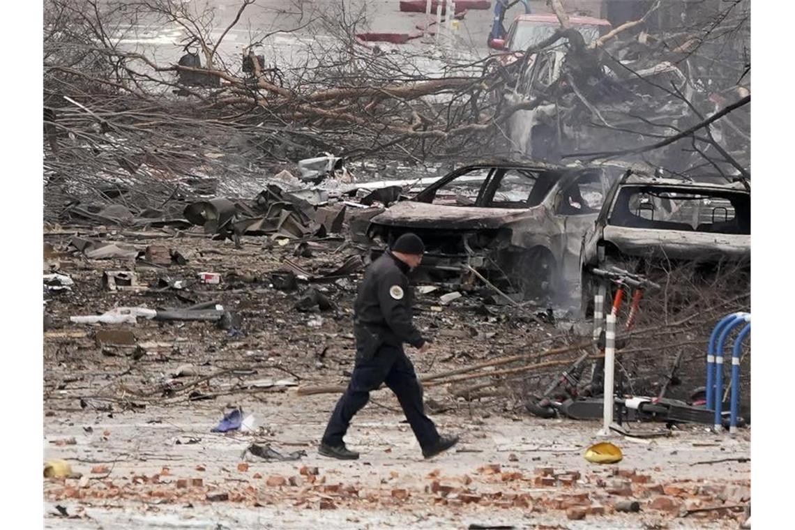 Trümmer und ausgebrannte Autos: Ein Mitglied der Einsatzkräfte am Ort des Geschehens. Foto: Mark Humphrey/AP/dpa