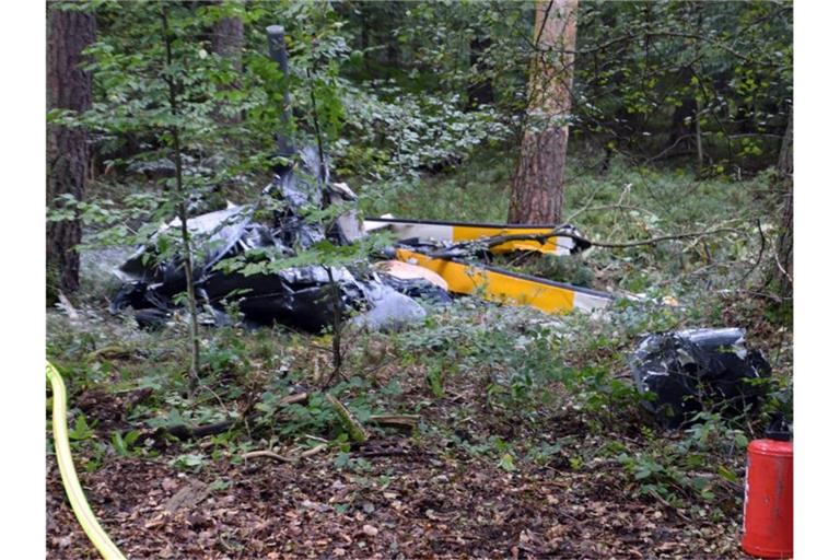 Trümmerteile eines Hubschraubers vom Typ Robinson R44 liegen in einem Wald. Foto: Julian Buchner/Einsatz-Report24/dpa