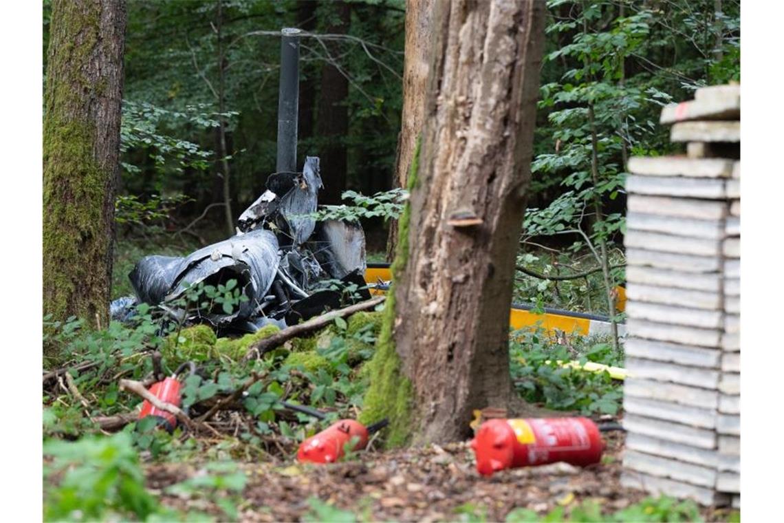 Trümmerteile eines Hubschraubers vom Typ Robinson R44 liegen in einem Wald. Foto: Sebastian Gollnow/dpa