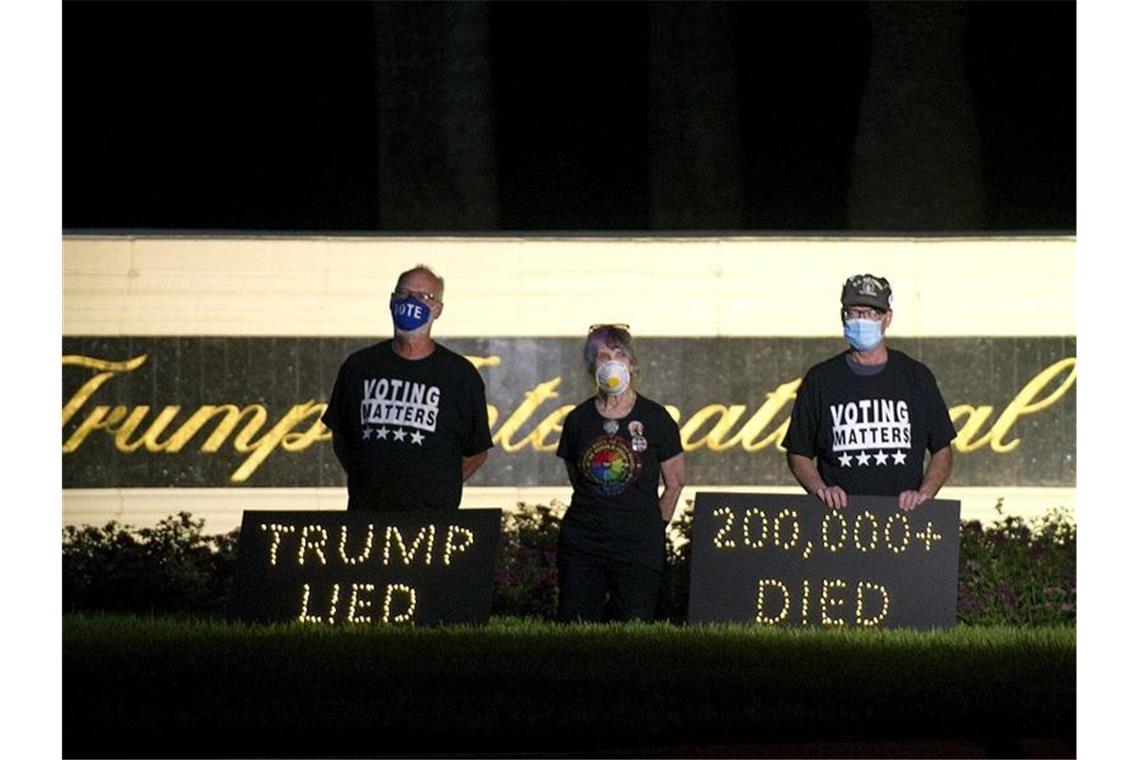 „Trump lied“ - „200.000 died“: Demonstranten halten in der Nähe des Trump International Golf Club in Palm Beach eine Mahnwache ab. Foto: Meghan Mccarthy/Palm Beach Post via ZUMA Wire/dpa
