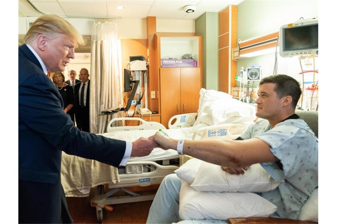 Proteste und Kritik bei Trumps Besuch in Dayton und El Paso Trump reicht einem Überlebenden des Massakers von Dayton die Hand. Foto: Shealah Craighead/White House