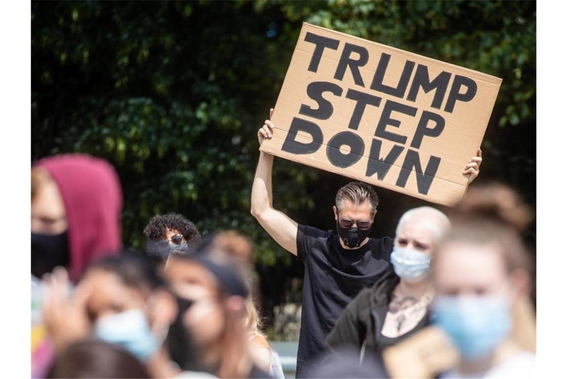 „Trump Step Down“ steht auf dem Schild eines Mannes, der an einer Demo gegen Rassismus teilnimmt. Foto: Christoph Schmidt/dpa/Archivbild