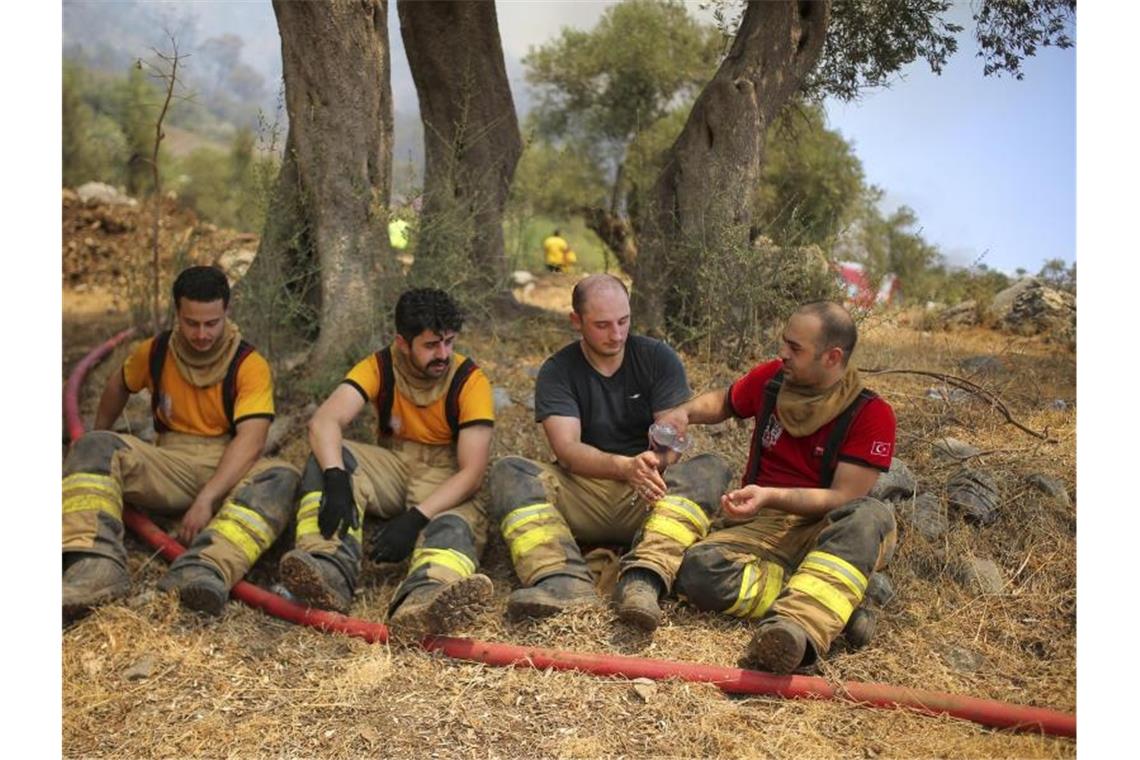 Türkische Feuerwehrleute machen eine Pause beim Einsatz in der Region Mugla. Foto: Emre Tazegul/AP/dpa