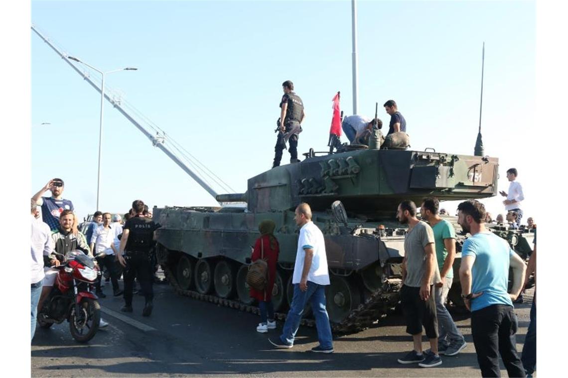 Türkische Polizisten und Anhänger von Präsident Erdogan stehen nach dem gescheiterten Putsch in der Nähe von Panzern auf der Bosporusbrücke in Istanbul. Foto: str/EPA