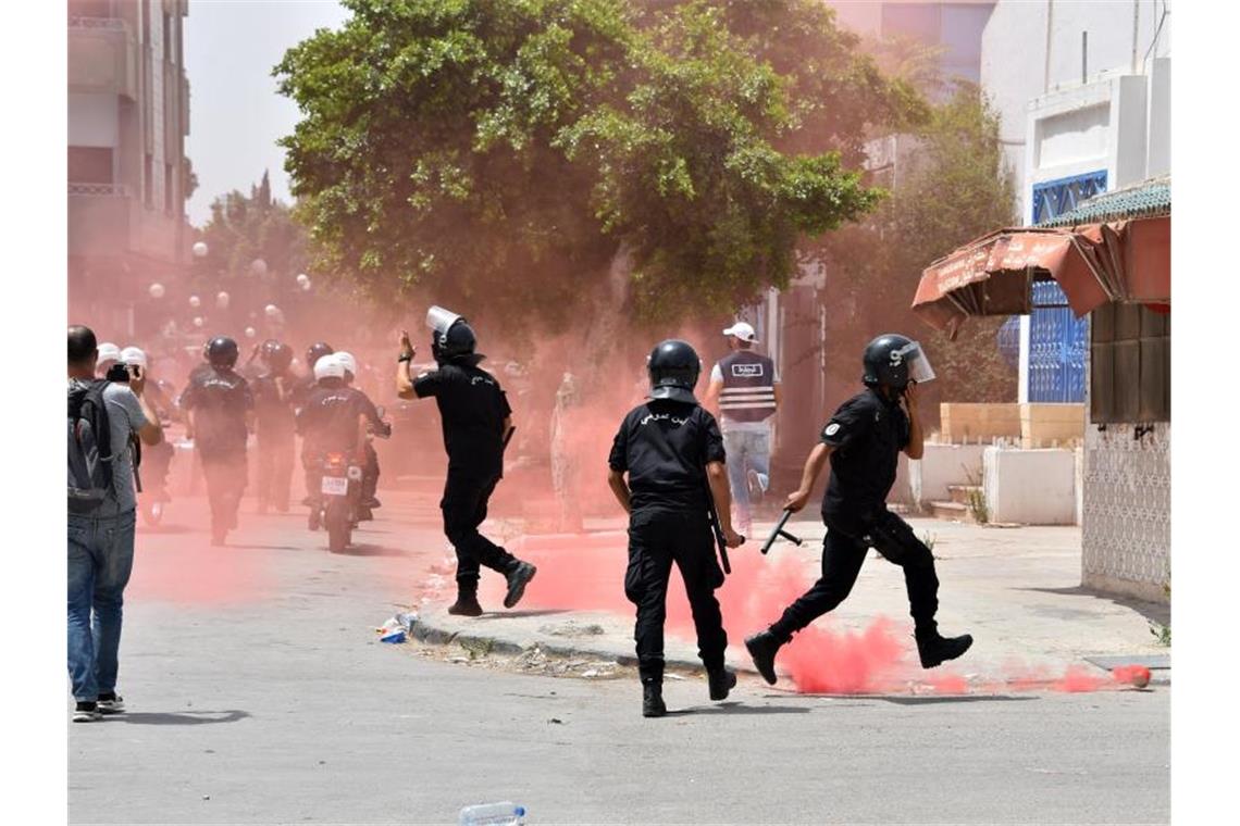 Tunesische Sicherheitskräfte werden während einer Demonstration vor dem Parlament von rotem Rauch eingehüllt. Foto: Jdidi Wassim/SOPA Images via ZUMA Press Wire/dpa