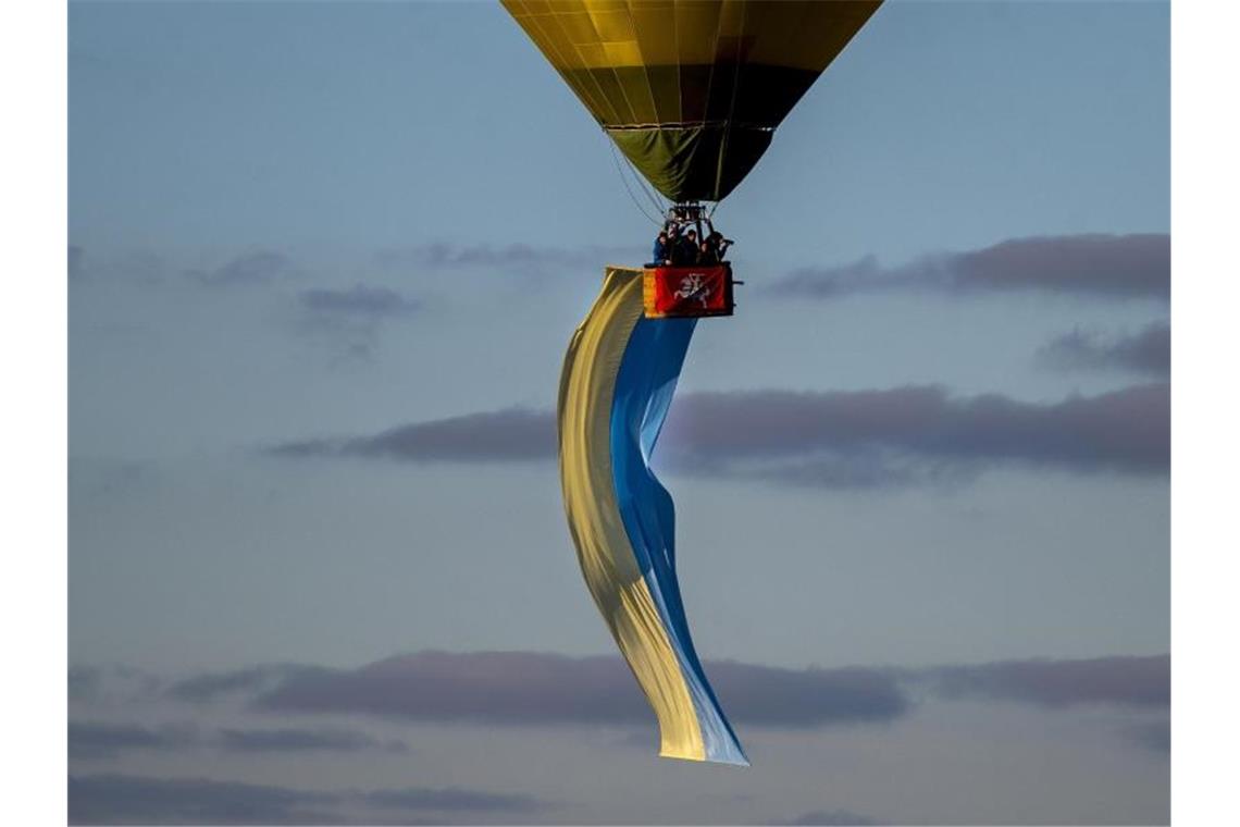 Erneut große Proteste gegen Ukraine-Krieg Über Litauens Hauptstadt Vilnius schwebt während der Proteste für den Frieden in der Ukraine ein Heißluftballon in den Farben der ukrainischen Flagge. Foto: Mindaugas Kulbis/AP/dpa