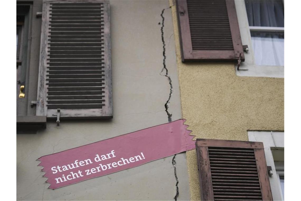 Über Riss in Hausfassade klebt Plakat mit der Aufschrift „Staufen darf nicht zerbrechen“. Foto: Patrick Seeger/dpa