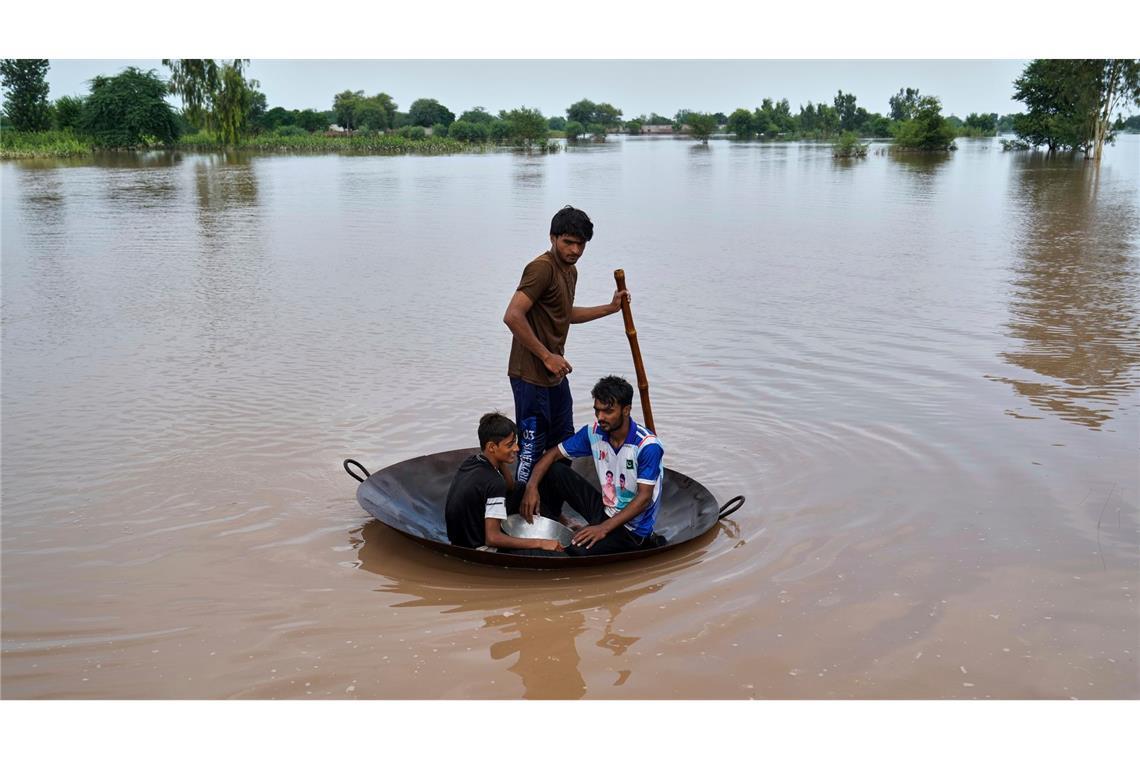Überschwemmung in Pakistan: Dorfbewohner benutzen eine große Metallkochpfanne zur Jaggery-Herstellung als behelfsmäßiges Floß