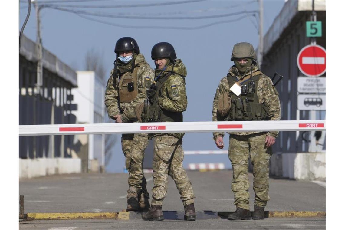 Putin erkennt Donezk und Luhansk als unabhängig an Ukrainische Grenzbeamte stehen an einem Kontrollpunkt zwischen dem Gebiet der prorussischen Separatisten und dem von den ukrainischen Streitkräften kontrollierten Gebiet. Foto: Evgeniy Maloletka/AP/dpa