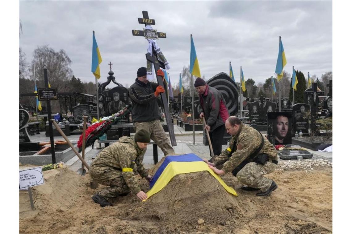 Russland setzt Angriff auf Mariupol fort Ukrainische Sanitäter bedecken das Grab einer von russischen Truppen getöteten Kollegin mit der Nationalflagge. Foto: Efrem Lukatsky/AP/dpa